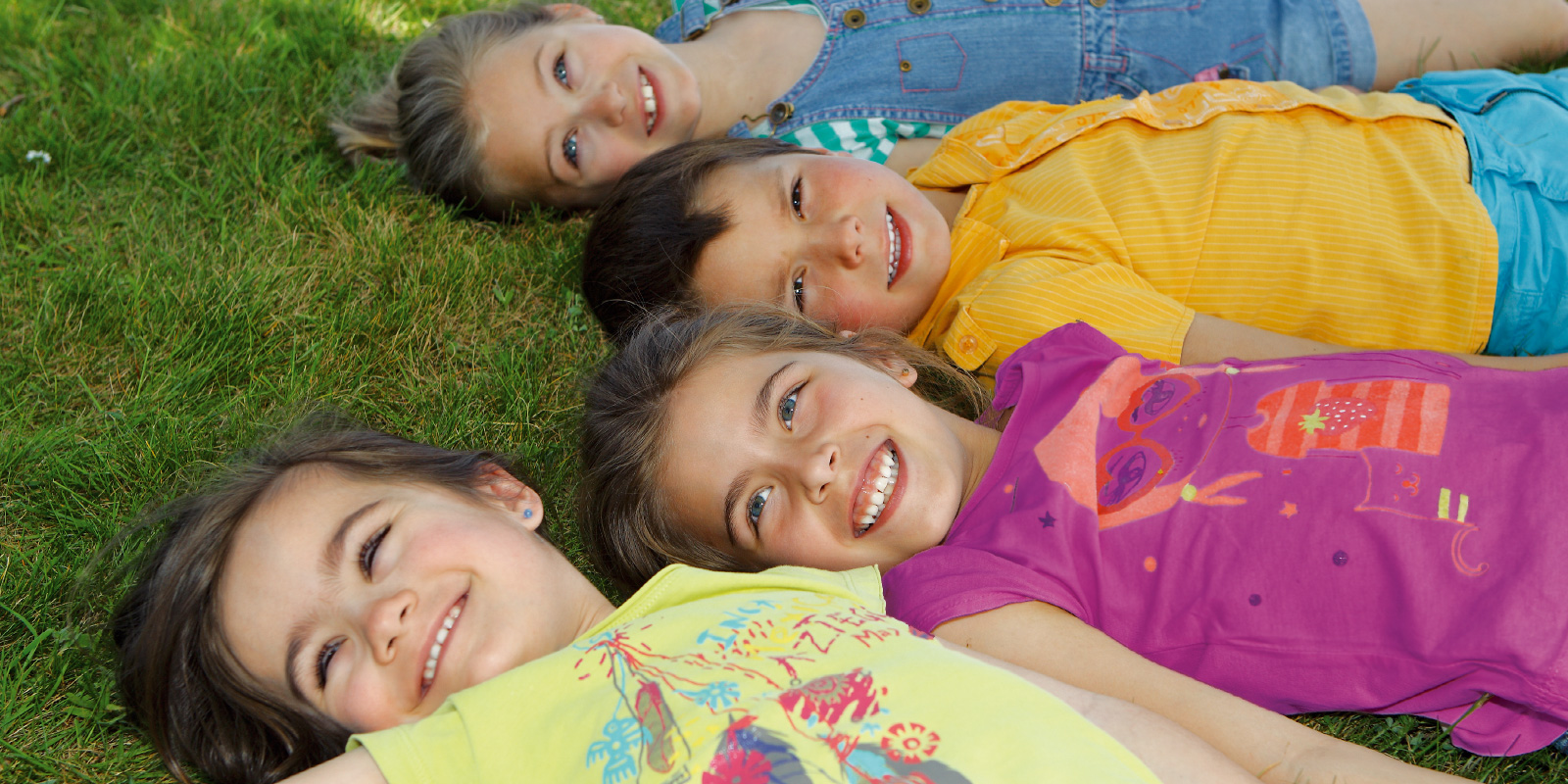 Enfants allongés sur l'herbe qui sourient blog wesco