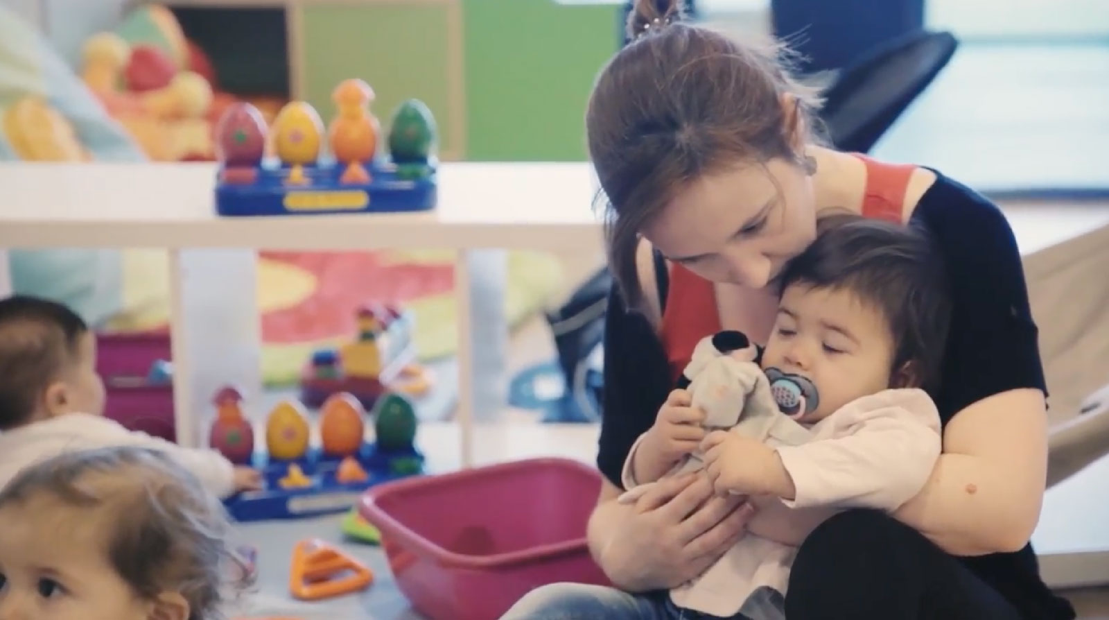 Femme qui tient un bébé entre ses jambes avec doudou et sucette blog Wesco