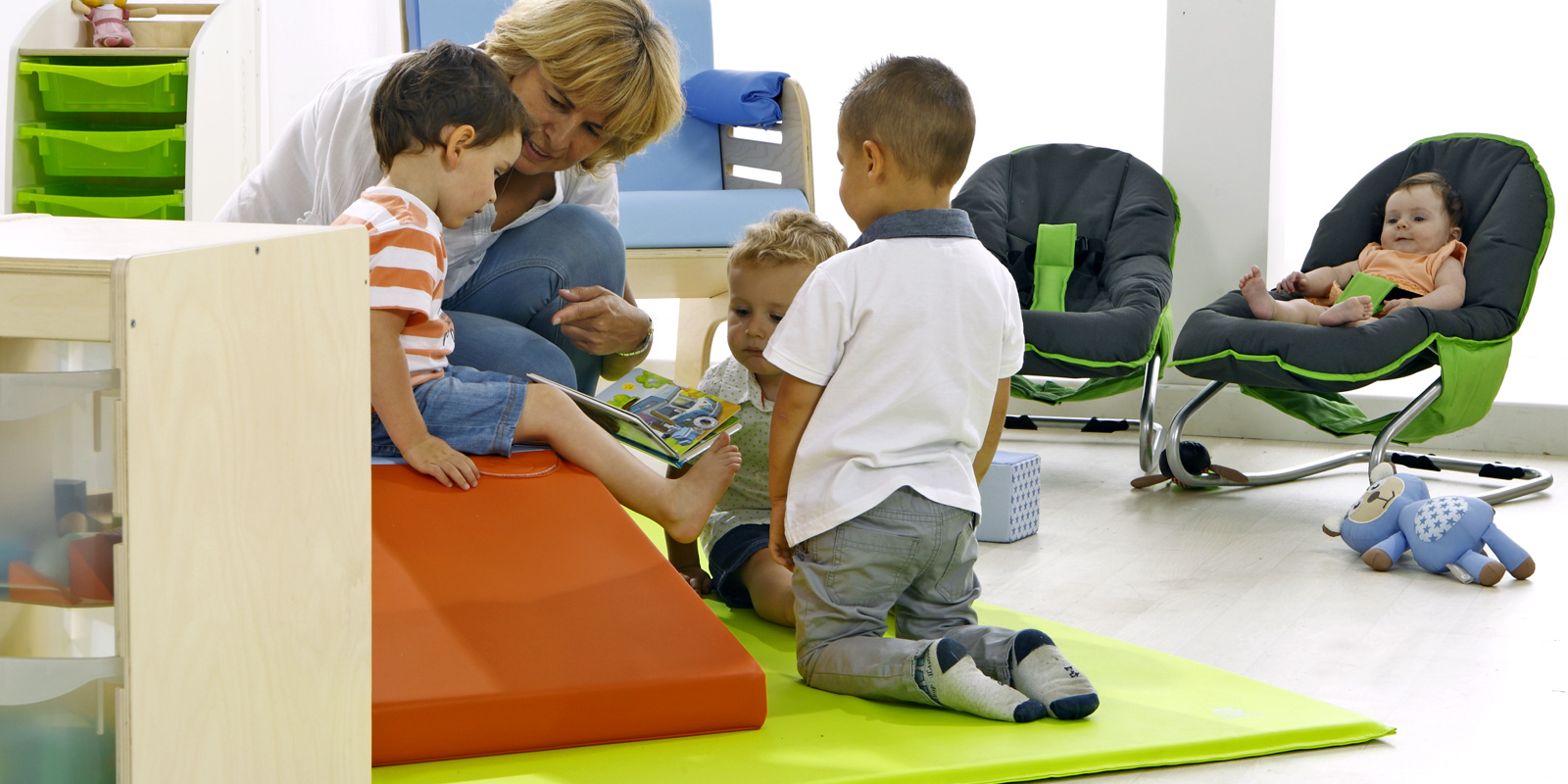 femme qui lit un livre à des enfants sur tapis et bébé dans un transat blog Wesco