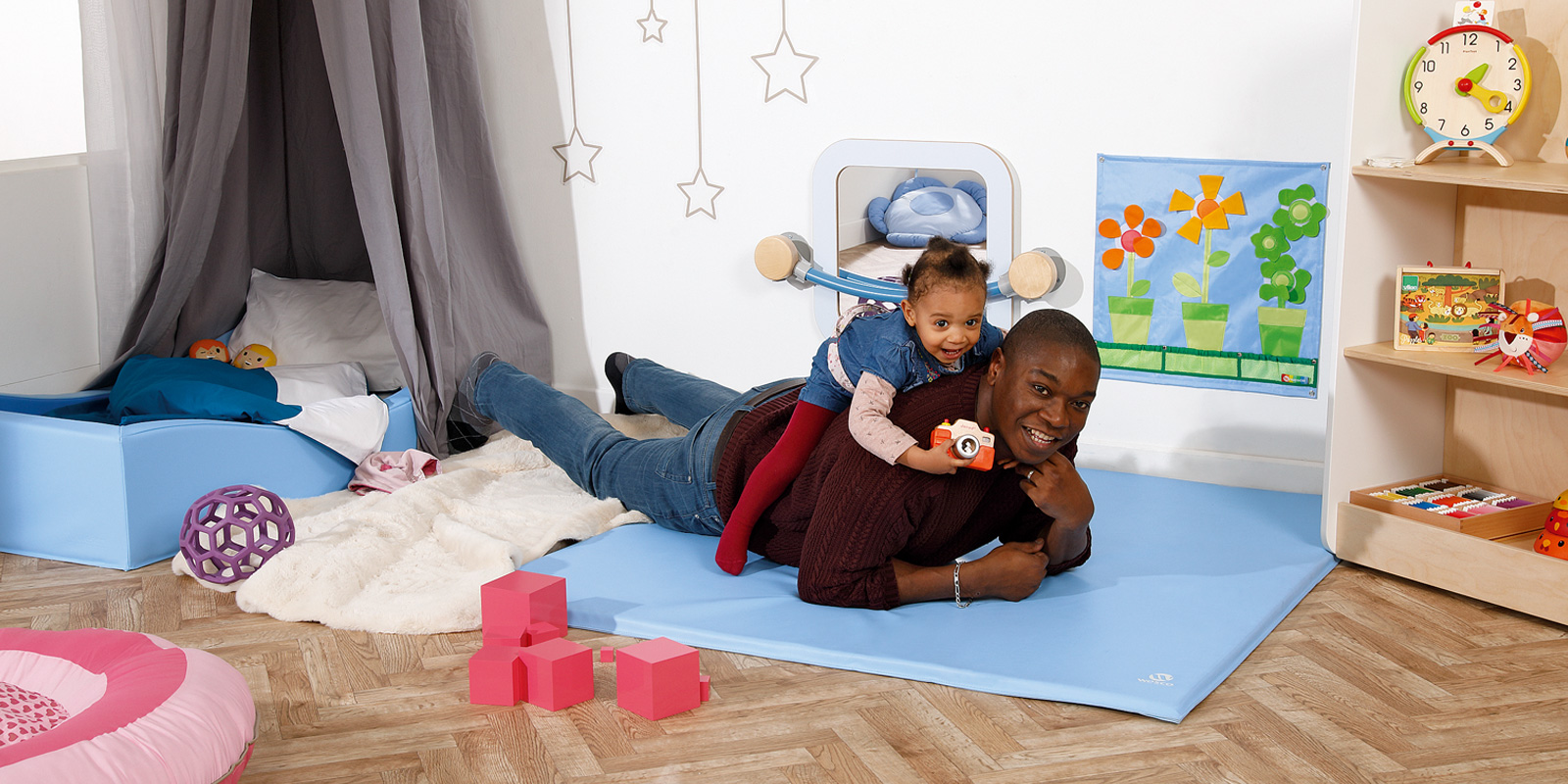 homme avec enfant sur le dos dans une chambre d'enfant sur tapis aménager une chambre Montessori blog wesco