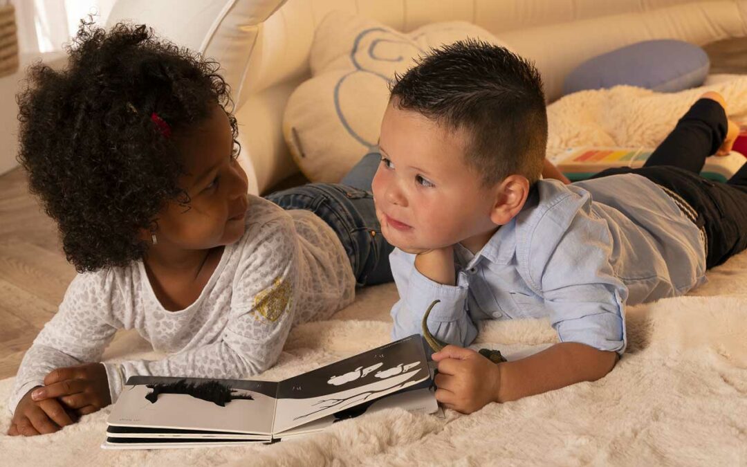 deux enfants sur tapis qui regardent un livre ensemble habiletés sociales blog wesco