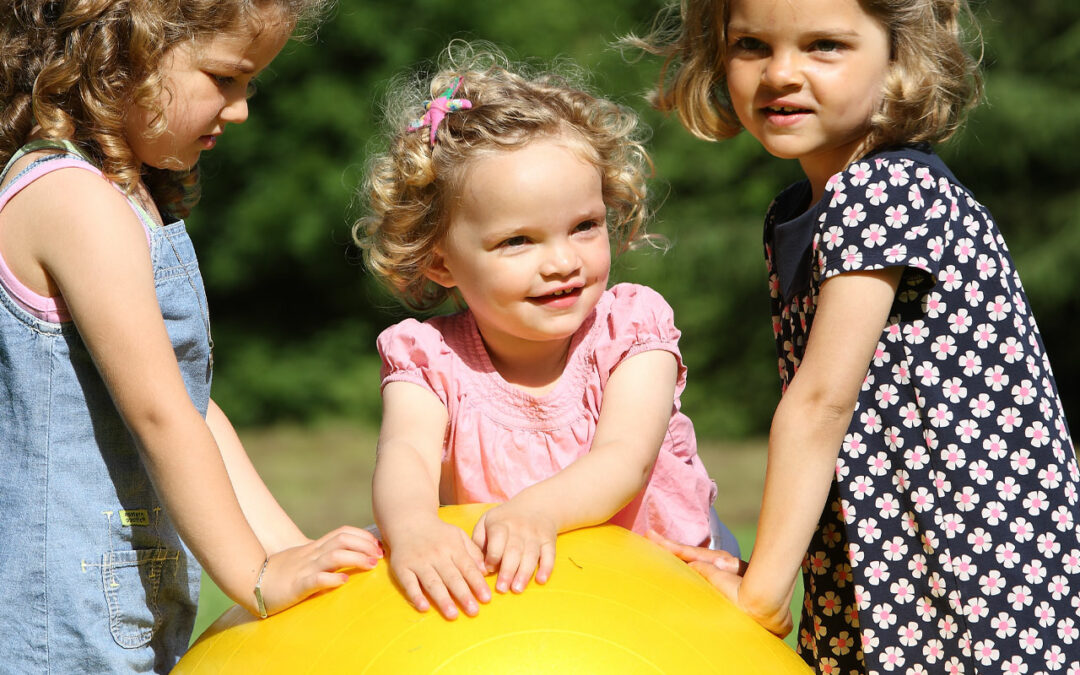 enfants en extérieur autour d'un gros ballon jaune activités coopération maternelle blog wesco